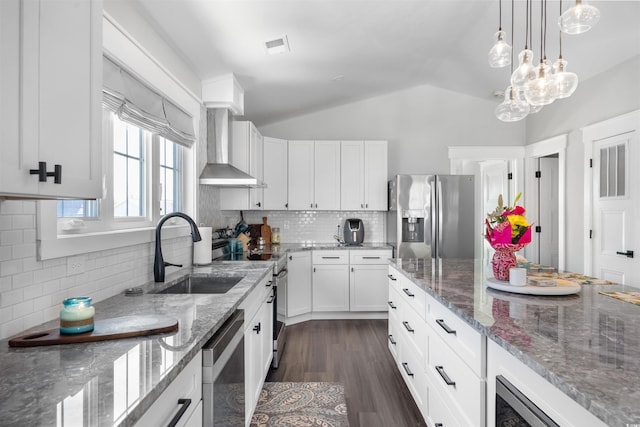 kitchen with dark wood-style flooring, a sink, vaulted ceiling, appliances with stainless steel finishes, and wall chimney exhaust hood