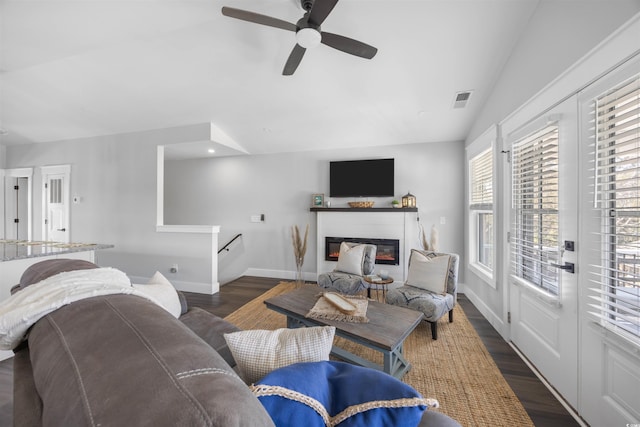 living room featuring visible vents, baseboards, lofted ceiling, wood finished floors, and a ceiling fan