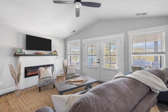 living room featuring french doors, lofted ceiling, visible vents, and a glass covered fireplace