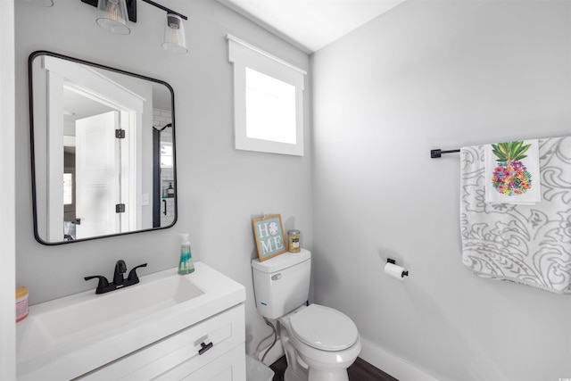 half bath with toilet, vanity, and baseboards