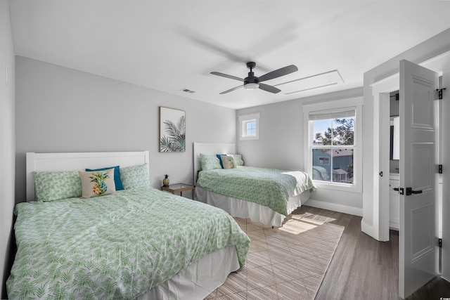 bedroom with a ceiling fan, wood finished floors, visible vents, and baseboards