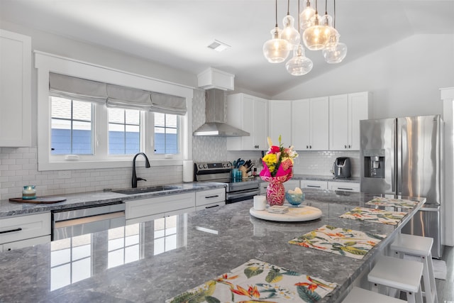 kitchen with visible vents, lofted ceiling, appliances with stainless steel finishes, wall chimney exhaust hood, and a sink