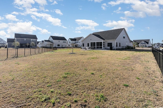 view of yard with a fenced backyard, a residential view, and a sunroom