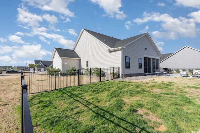 rear view of property with a sunroom, a yard, and fence