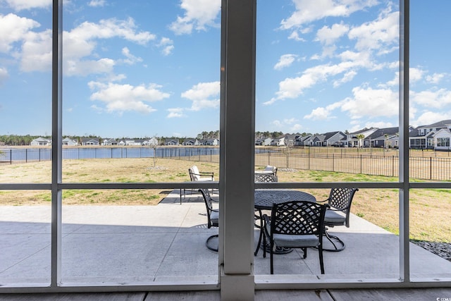 view of patio featuring a residential view, outdoor dining space, a water view, and fence