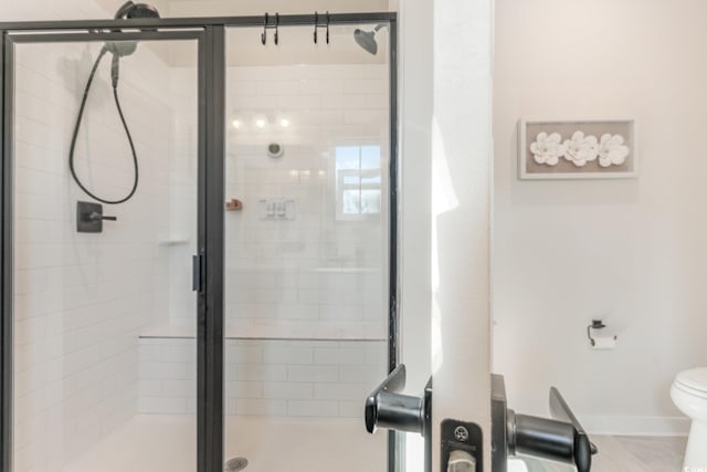 full bathroom with baseboards, toilet, and a shower stall