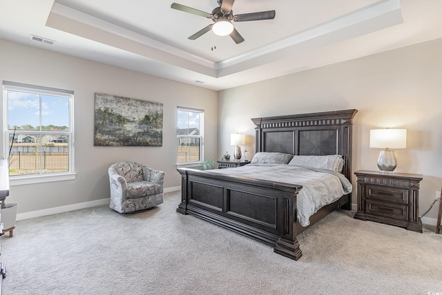 carpeted bedroom with a raised ceiling, multiple windows, and visible vents