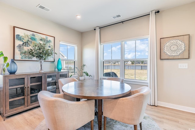 dining space featuring visible vents, baseboards, and light wood finished floors