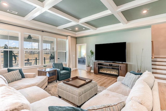 living room with beam ceiling, coffered ceiling, light wood-type flooring, and baseboards