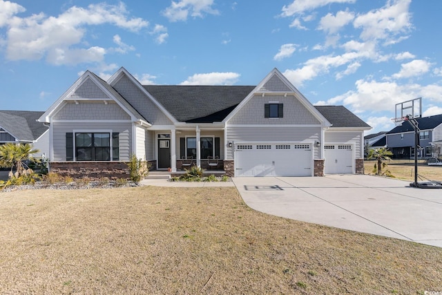 craftsman-style home with stone siding, covered porch, driveway, and a front lawn