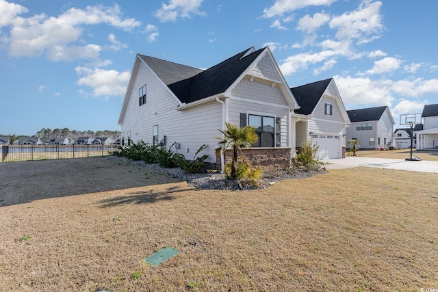 view of home's exterior with fence, driveway, stone siding, a lawn, and a residential view