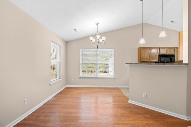 kitchen with light wood-type flooring, visible vents, a notable chandelier, black microwave, and vaulted ceiling