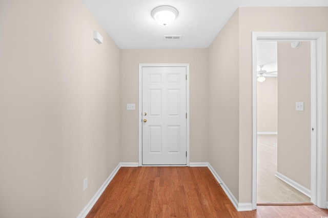 corridor featuring visible vents, baseboards, and wood finished floors