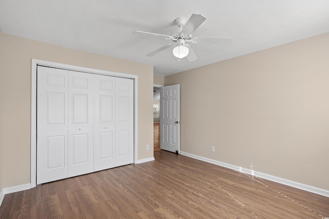 unfurnished bedroom featuring wood finished floors, baseboards, a closet, and ceiling fan