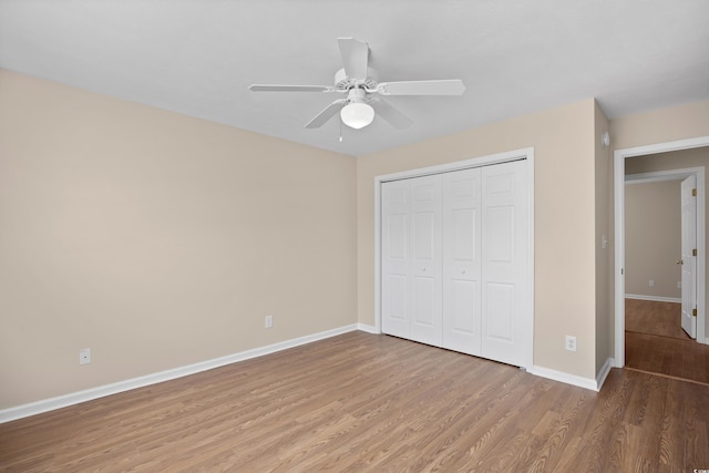 unfurnished bedroom with a closet, ceiling fan, baseboards, and wood finished floors