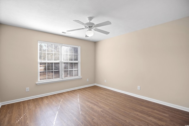 unfurnished room featuring visible vents, baseboards, wood finished floors, and a ceiling fan