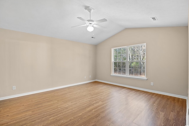 spare room featuring baseboards, wood finished floors, a ceiling fan, and vaulted ceiling