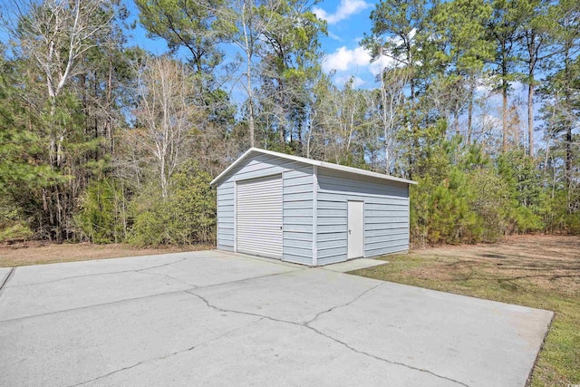 detached garage featuring a wooded view and concrete driveway