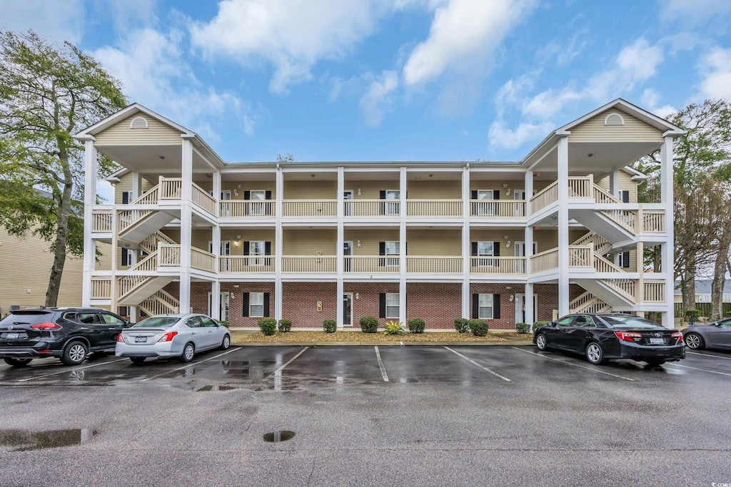 view of building exterior with stairway and uncovered parking