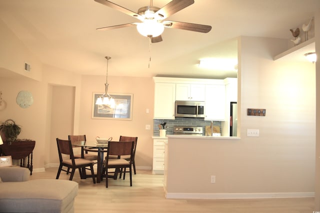 dining space featuring light wood-type flooring, visible vents, baseboards, and ceiling fan