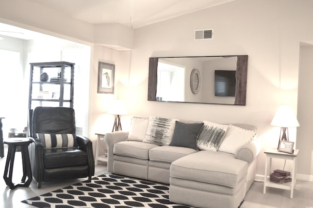 living area with baseboards, vaulted ceiling, visible vents, and a ceiling fan
