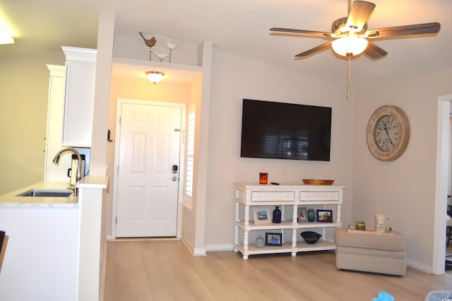 living area featuring ceiling fan, vaulted ceiling, light wood finished floors, and baseboards