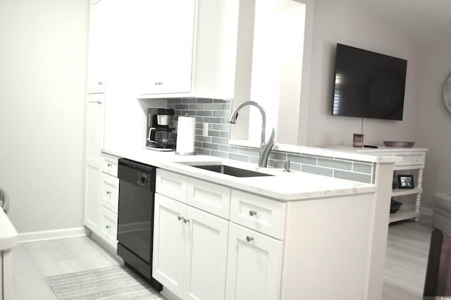 kitchen featuring white cabinets, dishwasher, a sink, light wood-style flooring, and tasteful backsplash