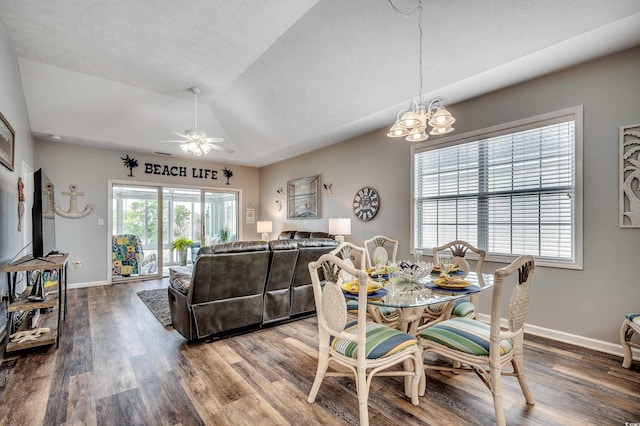 dining room with ceiling fan with notable chandelier, wood finished floors, baseboards, and vaulted ceiling