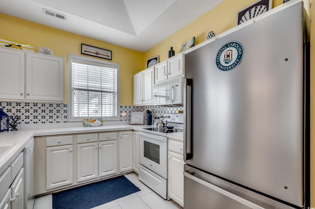 kitchen with visible vents, backsplash, white appliances, white cabinets, and light tile patterned floors