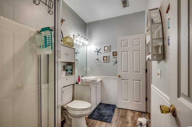 bathroom featuring visible vents, a stall shower, wood finished floors, and a wainscoted wall