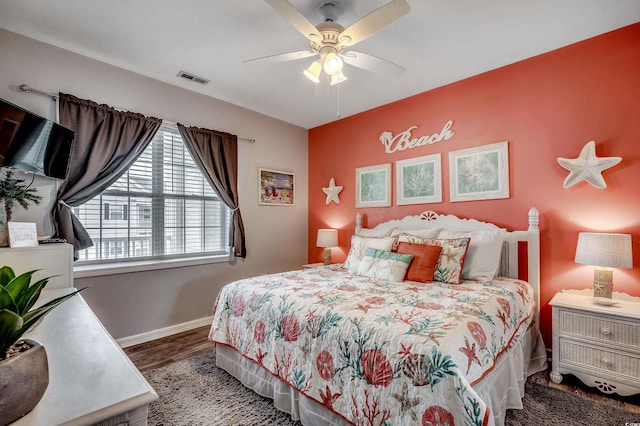 bedroom with ceiling fan, wood finished floors, visible vents, and baseboards