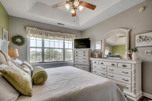 bedroom featuring a tray ceiling, visible vents, and ceiling fan