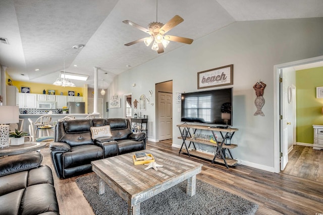 living room with ceiling fan with notable chandelier, wood finished floors, and vaulted ceiling