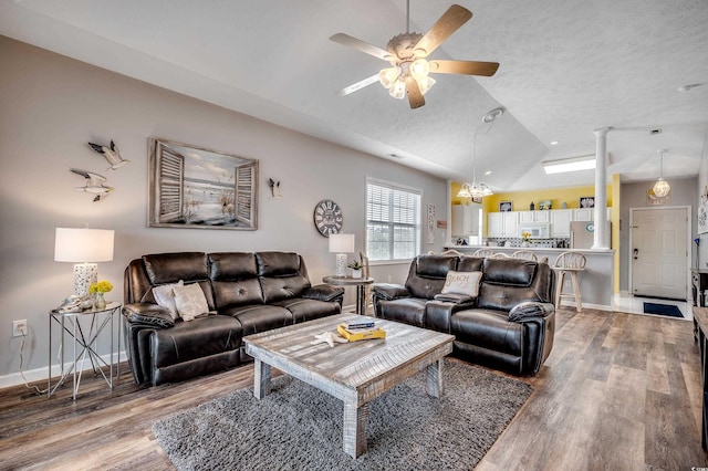 living area featuring light wood-type flooring, lofted ceiling, baseboards, and ceiling fan with notable chandelier