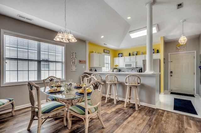 dining space with visible vents, an inviting chandelier, lofted ceiling, and ornate columns