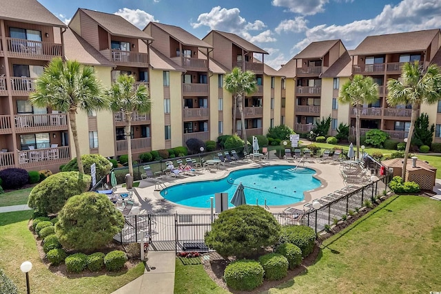 community pool with a patio area and fence