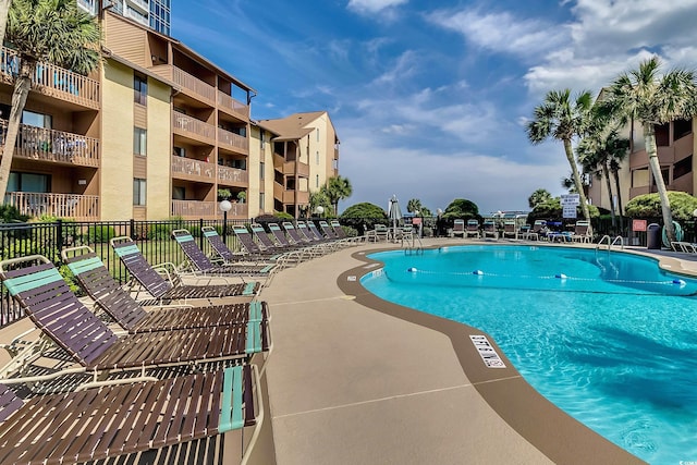 community pool with a patio area and fence