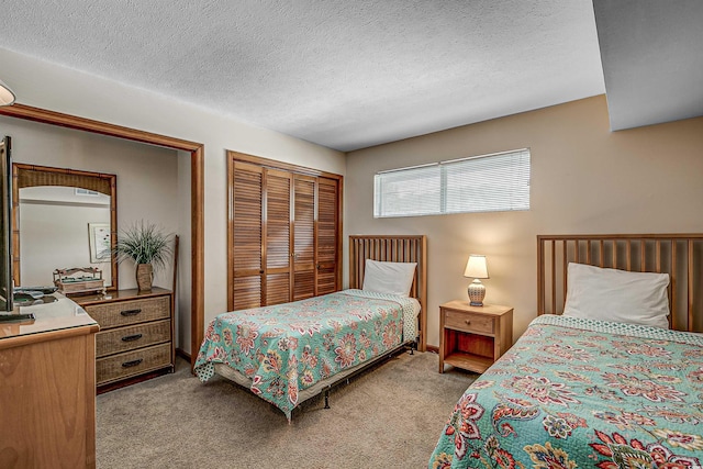 bedroom with light colored carpet, two closets, and a textured ceiling