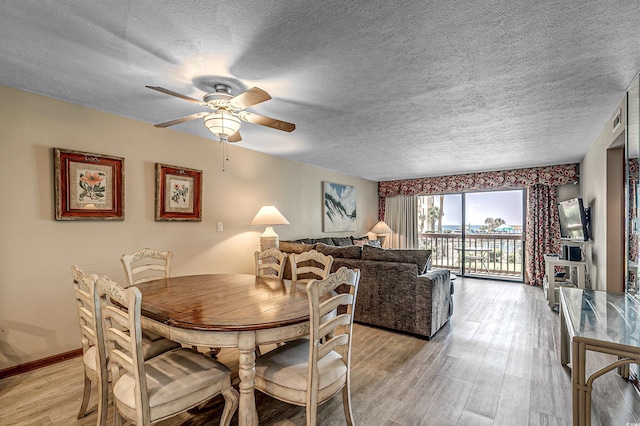 dining area with baseboards, a textured ceiling, light wood-style flooring, and a ceiling fan