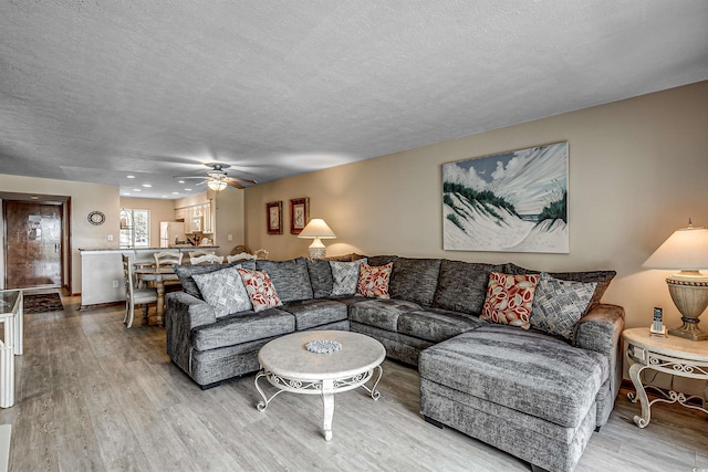 living room with a textured ceiling, wood finished floors, and ceiling fan