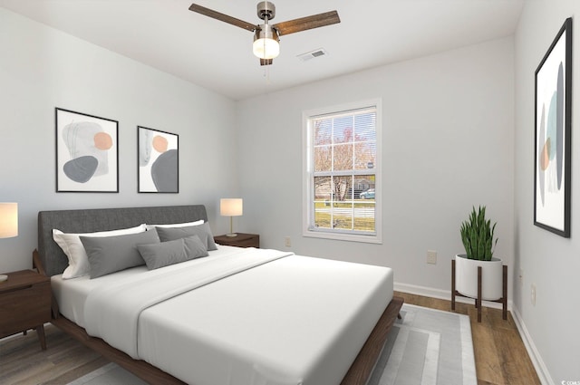 bedroom featuring visible vents, a ceiling fan, baseboards, and wood finished floors