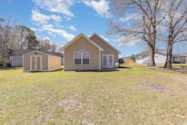 back of house featuring an outdoor structure, a yard, french doors, and a shed