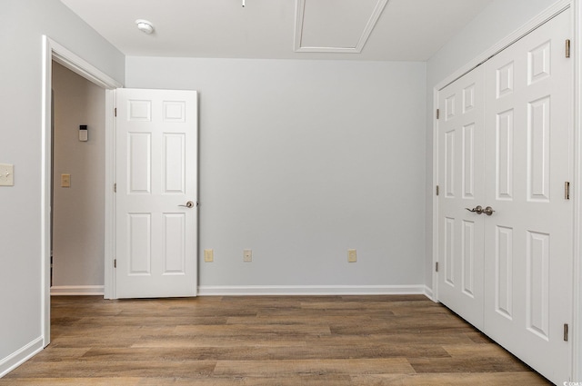 unfurnished bedroom featuring a closet, baseboards, and wood finished floors