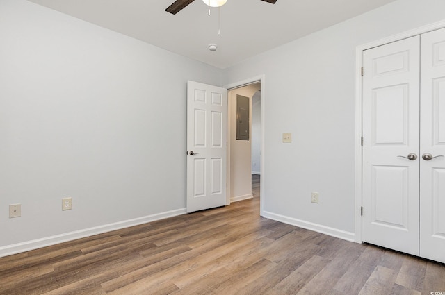 unfurnished bedroom featuring wood finished floors, baseboards, a closet, and ceiling fan