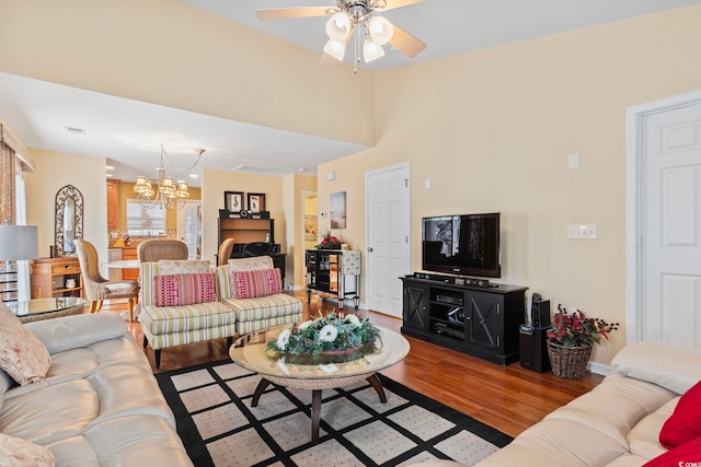 living area featuring baseboards, wood finished floors, and ceiling fan with notable chandelier