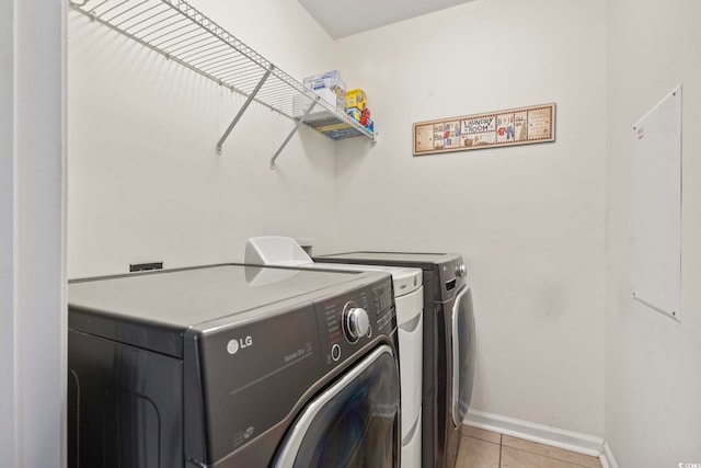 washroom featuring laundry area, light tile patterned floors, baseboards, and washer and clothes dryer