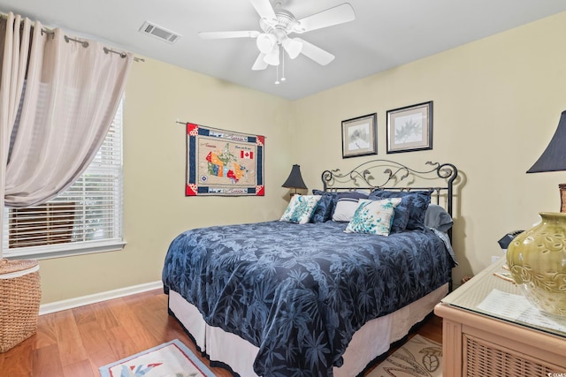 bedroom featuring visible vents, ceiling fan, baseboards, and wood finished floors