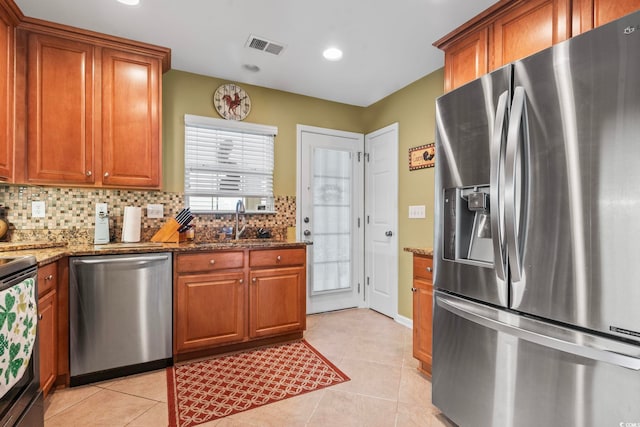 kitchen with visible vents, backsplash, dark stone counters, appliances with stainless steel finishes, and brown cabinetry