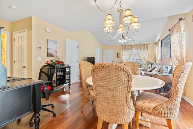 dining space with baseboards, wood finished floors, an inviting chandelier, and vaulted ceiling