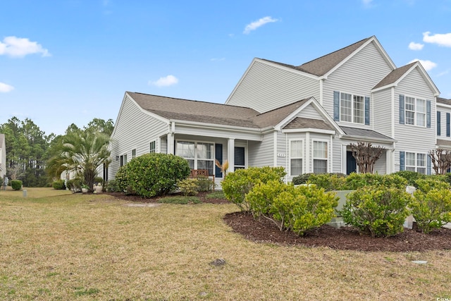 traditional home featuring roof with shingles and a front yard